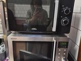 someone is taking a picture of a microwave on a small table