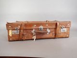 a brown suitcase sitting on a table with a tag on it