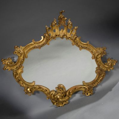 an ornately carved mirror with a gold frame on a grey background