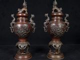 pair of bronze vases with dragon heads on each of them