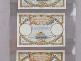 Trois types différents de billets de banque sont exposés dans une vitrine.
