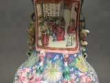 a vase with a painting on it sitting on a table
