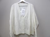 the white cardigan sweater is hanging on a hanger on a wall
