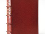 a red leather book with three books on top of it