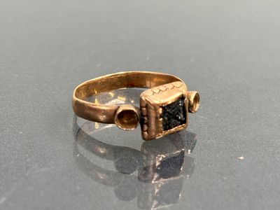 gros plan d'une bague en or contenant une pierre noire