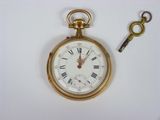 a gold pocket watch and a key on a white surface