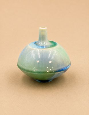 un vase bleu et vert posé sur une surface marron