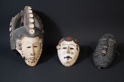 three masks on a black surface with a black background