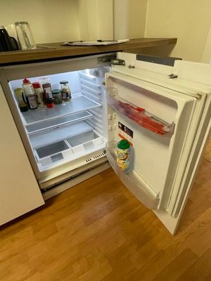an open refrigerator in the corner of a kitchen