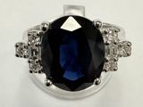 a picture of a ring with a large blue stone surrounded by small white diamonds