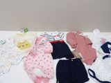 de nombreux vêtements de bébé disposés sur une table blanche