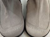 des bottines grises à pompons, posées sur une surface blanche