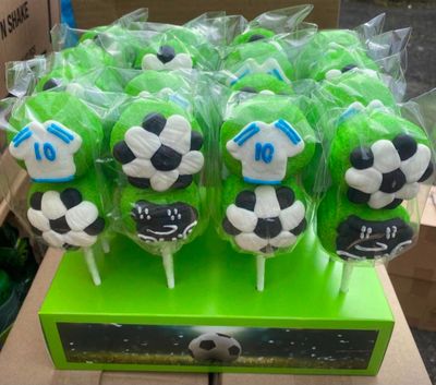 des sucettes sur le thème du football, vertes et noires, présentées dans une boîte