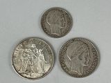 three silver coins sitting next to each other on a white surface