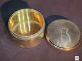 a small metal container with a lid on a table