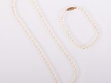 a white necklace and a gold chain on a white background