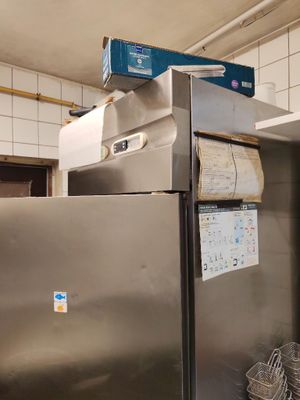 un réfrigérateur en acier inoxydable dans une cuisine, surmonté d'un panier
