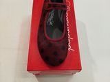 une boîte rouge sur laquelle est posée une paire de chaussures, posée sur une surface blanche