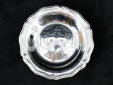 une assiette ancienne en argent sur fond noir, avec une cuillère en argent au centre
