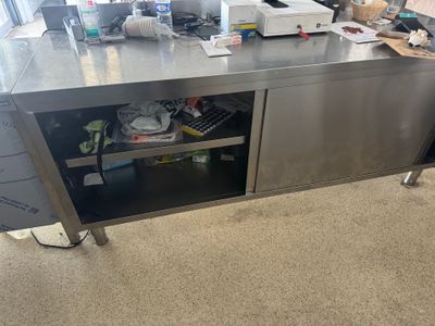 une grande table de travail en acier inoxydable équipée de tiroirs et d'une imprimante