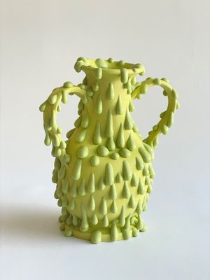un vase jaune posé sur une surface blanche
