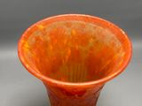 an orange vase sitting on a table with a gray background