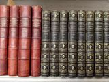 several old books are lined up on a shelf in a library