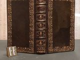 an old book with a leather cover sitting on top of a table