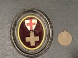 a medal with a cross on it next to a coin