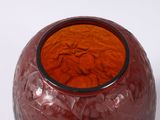a red vase with a black rim sitting on a white surface