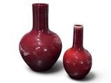 deux vases rouges posés l'un à côté de l'autre sur une surface blanche