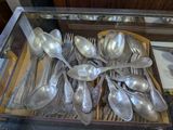 many silver spoons and spoon spoons in a glass case