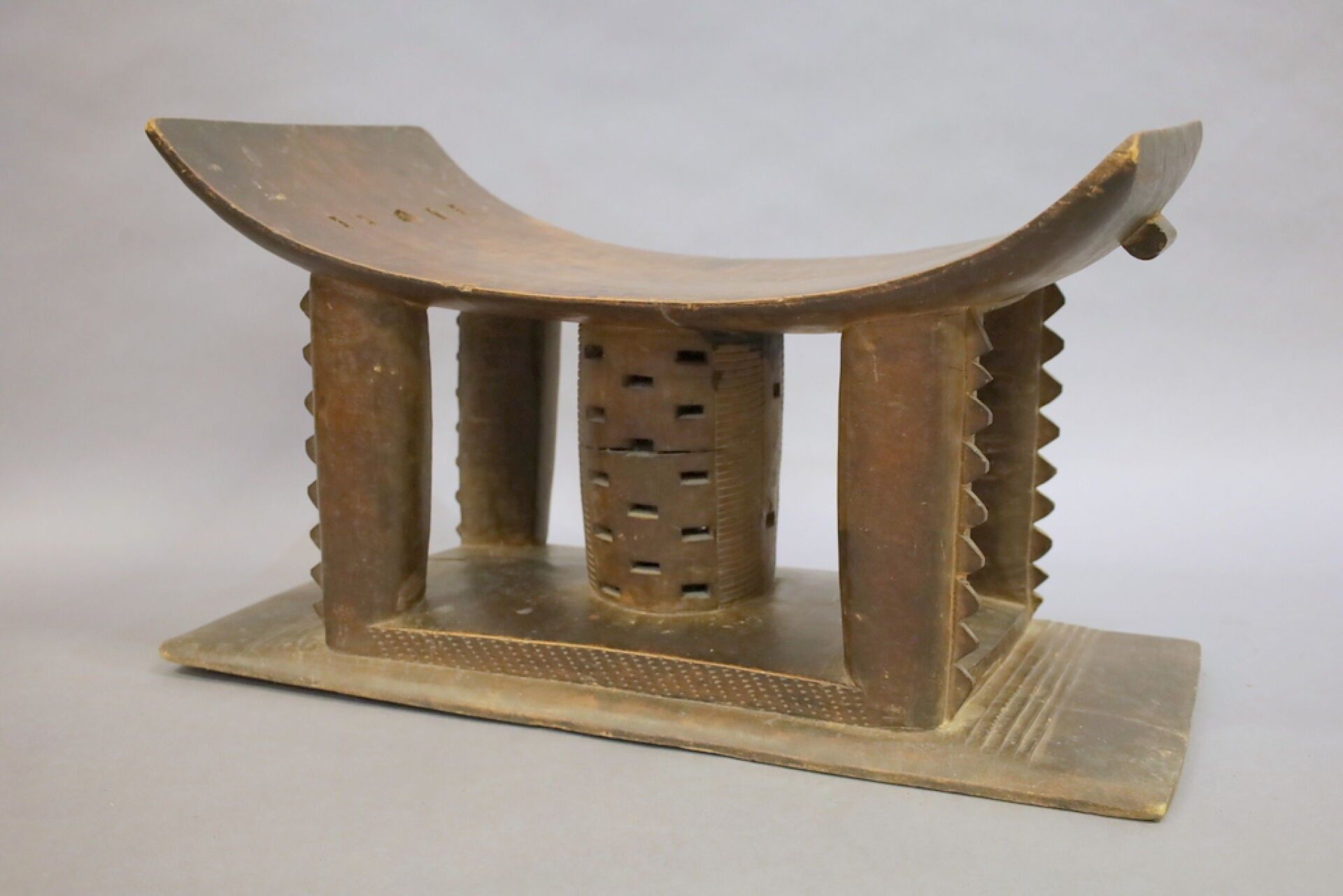 ASHANTI, Gana. Tabouret traditionnel en bois exotique, reposant sur quatre colonnes et piètement central ajouré évoqu...