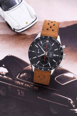 la montre est posée sur un magazine, avec une voiture en arrière-plan