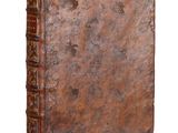 an old book with a brown cover sitting on top of a white surface