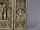 two carved ivory panels with figures on them on a gray surface
