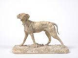 statue of a dog standing on a rock on a white background