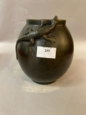 a black vase with a lizard on it on a white surface