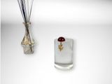 a glass vase with a flower in it next to a vase with sticks