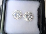 two diamond stud earrings in a black box on a white surface