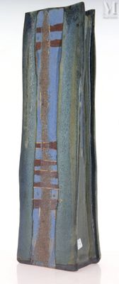 un vase bleu et brun posé sur une surface blanche