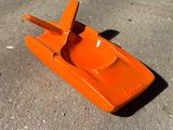 un petit bateau en plastique orange posé par terre