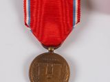 an old medal with a red ribbon on a white surface