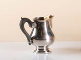 a silver pitcher sitting on a table next to a vase