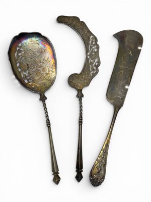 two silver spoons and a knife on a white surface