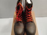 pair of black boots with orange laces on top of a cardboard box