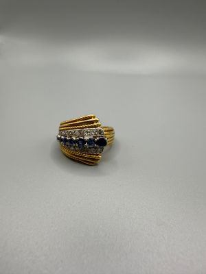 gros plan d'une bague en or avec des pierres bleues et blanches