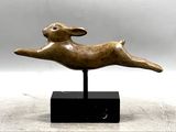 statue représentant un chien bondissant dans les airs, posée sur un socle noir