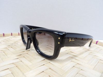 une paire de lunettes de soleil noires posée sur un panier en osier