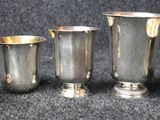 four silver cups are lined up on a black surface